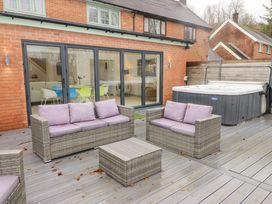 An outdoor patio with wicker furniture and a hot tub at Hiraeth in Cwmtaf near Cefn-Coed-Y-Cymmer