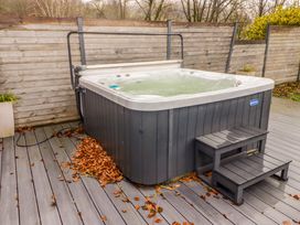 An outdoor hot tub with steps on a deck surrounded by a wooden fence at Hiraeth in Cwmtaf near Cefn-Coed-Y-Cymmer
