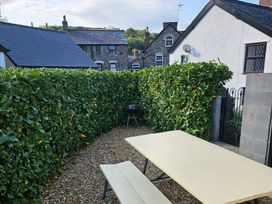 A garden with a table and bench surrounded by a hedge at Dove Cottage Llanfair Talhaiarn