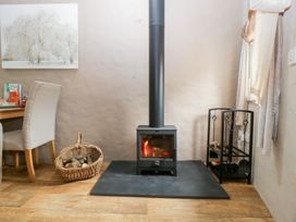 A living room with a stove and table at Caner Bach Lodge Blackmill