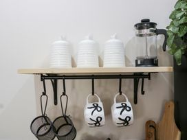 A kitchen shelf with canisters and mugs at Caner Bach Lodge in Blackmill