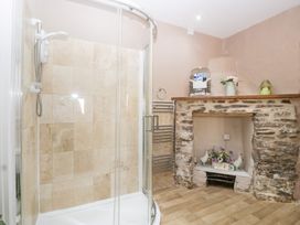 A bathroom with a shower and stone fireplace at Caner Bach Lodge in Blackmill