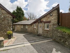 An entrance area with a stone wall and driveway at Caner Bach Lodge in Blackmill