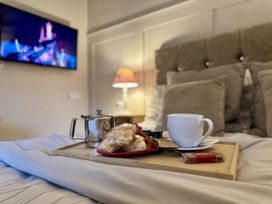 A breakfast tray with tea and pastries on a bed at Caner Bach Lodge Blackmill