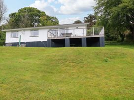 A house with a deck and benches on grass at The Meadow in Feock near Carnon Downs