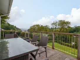 A patio area with a table and chairs overlooking water at The Meadow in Feock near Carnon Downs
