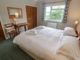 A bedroom with a bed, table, and lamp at The Meadow in Feock near Carnon Downs