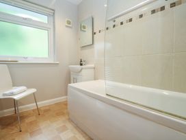 A bathroom with a bath, shower, sink and chair at The Meadow Feock near Carnon Downs