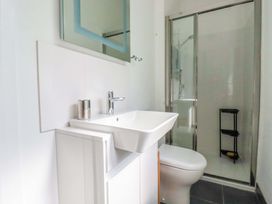 A bathroom with sink, toilet, shower and storage shelf at Pentreath in Crantock