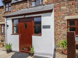 An entrance with a wooden door and stone wall at Carpe Diem in Crantock