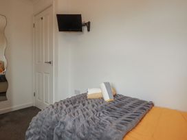A bedroom with a bed and a television mounted on the wall at Carpe Diem in Crantock