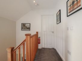 A hallway with a staircase and photographs on the wall at Carpe Diem in Crantock