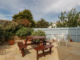 A garden with a wooden table and benches at Carpe Diem in Crantock