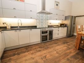 A kitchen with cabinets, sink, kettle, cooker and refrigerator at The Turnip Barn in 