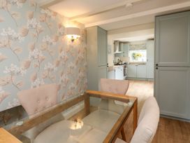 A dining room with a table and chairs leading to a kitchen at Tan Y Goeden in Morfa Nefyn