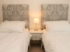 A bedroom with two beds and a lamp at Tan Y Goeden in Morfa Nefyn