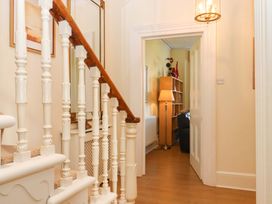 A hallway with a staircase and a bookcase at Avenue Park Villa Torquay