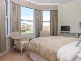 A bedroom with two armchairs and a television at Avenue Park Villa in Torquay
