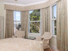 A bedroom with a bed and chairs at Avenue Park Villa in Torquay