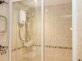A shower with glass doors and a showerhead at Avenue Park Villa in Torquay