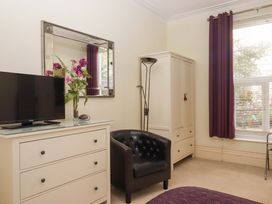 A bedroom with a TV, dresser, and chair at Avenue Park Villa in Torquay