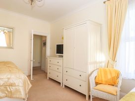 A bedroom with a bed, wardrobe, chest of drawers, and television at Avenue Park Villa in Torquay