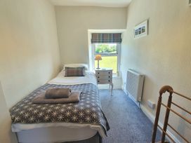 A small bedroom with a single bed a side table lamp window with a view and a radiator at Moelwyn View Cottage in Llan Ffestiniog