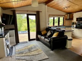A living room with a sofa and kitchen area at Willow Lodge in Constantine near Falmouth