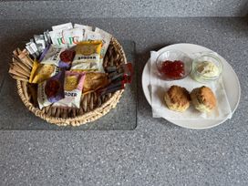 A basket with biscuits and a plate with scones, jam, and cream at Willow Lodge in Constantine near Falmouth