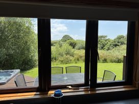 A view from a kitchen window showing a hot tub and seating area at Willow Lodge in Constantine near Falmouth