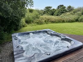 A hot tub on decking in a garden at Willow Lodge in Constantine near Falmouth