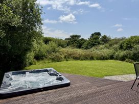 A hot tub on a deck with garden view at Willow Lodge in Constantine near Falmouth