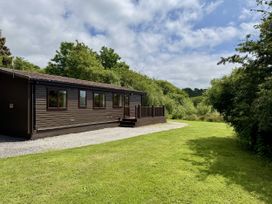 A lodge with a deck and a gravel path at Willow Lodge Constantine near Falmouth
