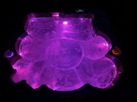 A hot tub filled with water and illuminated with purple lights at Willow Lodge in Constantine near Falmouth