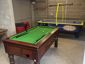 A game room with a pool table and air hockey table at Westpoint in Llandudno