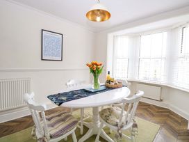 A dining room with a table, chairs, and a vase of tulips at Springfield in Hempton near Fakenham