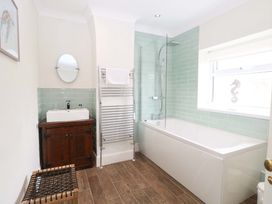 A bathroom with a bath tub, sink, and towel rack at Springfield in Hempton near Fakenham
