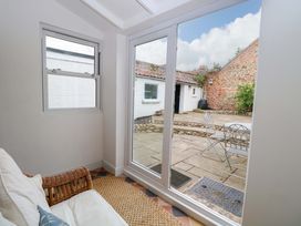 A conservatory with a sofa and view of patio at Springfield in Hempton near Fakenham
