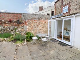 A garden with a table and chairs near a brick wall at Springfield, Hempton near Fakenham