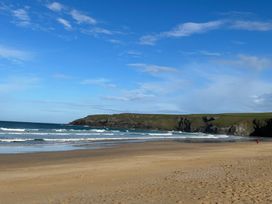 A beach with waves and cliffs at Holywell Bay View in Holywell Bay