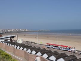 A beach with beach huts and people at Apt 2 @ Hunter's Quay Bridlington