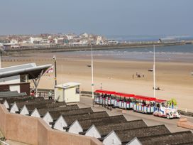 A coastal area with beach huts and a train at Apt 5 @ Hunter's Quay in Bridlington