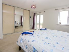 A bedroom featuring a bed with bedding and mirrored wardrobe at Welymora in Pwllheli