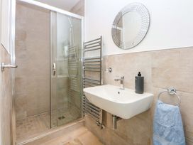 A bathroom with a shower, sink, mirror and towel rack at Welymora Pwllheli
