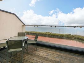 An outdoor balcony with a table and chairs overlooking the sea at Welymora Pwllheli