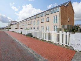 A building with multiple windows and a fence along a road at Welymora, Pwllheli