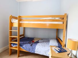 A bunk bed with a blue mattress and a book on a nightstand at Tilly's Retreat in Hunstanton