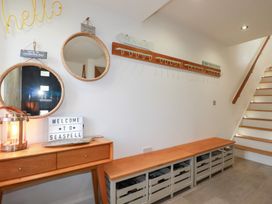 An entrance with mirrors, a lamp, a welcome sign, and a coat rack at Seaspell Beach House in Constantine Bay
