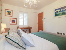 A bedroom with a bed, desk, and artworks at Seaspell Beach House in Constantine Bay