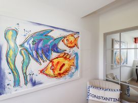 A room with a fish painting and a sofa at Seaspell Beach House in Constantine Bay